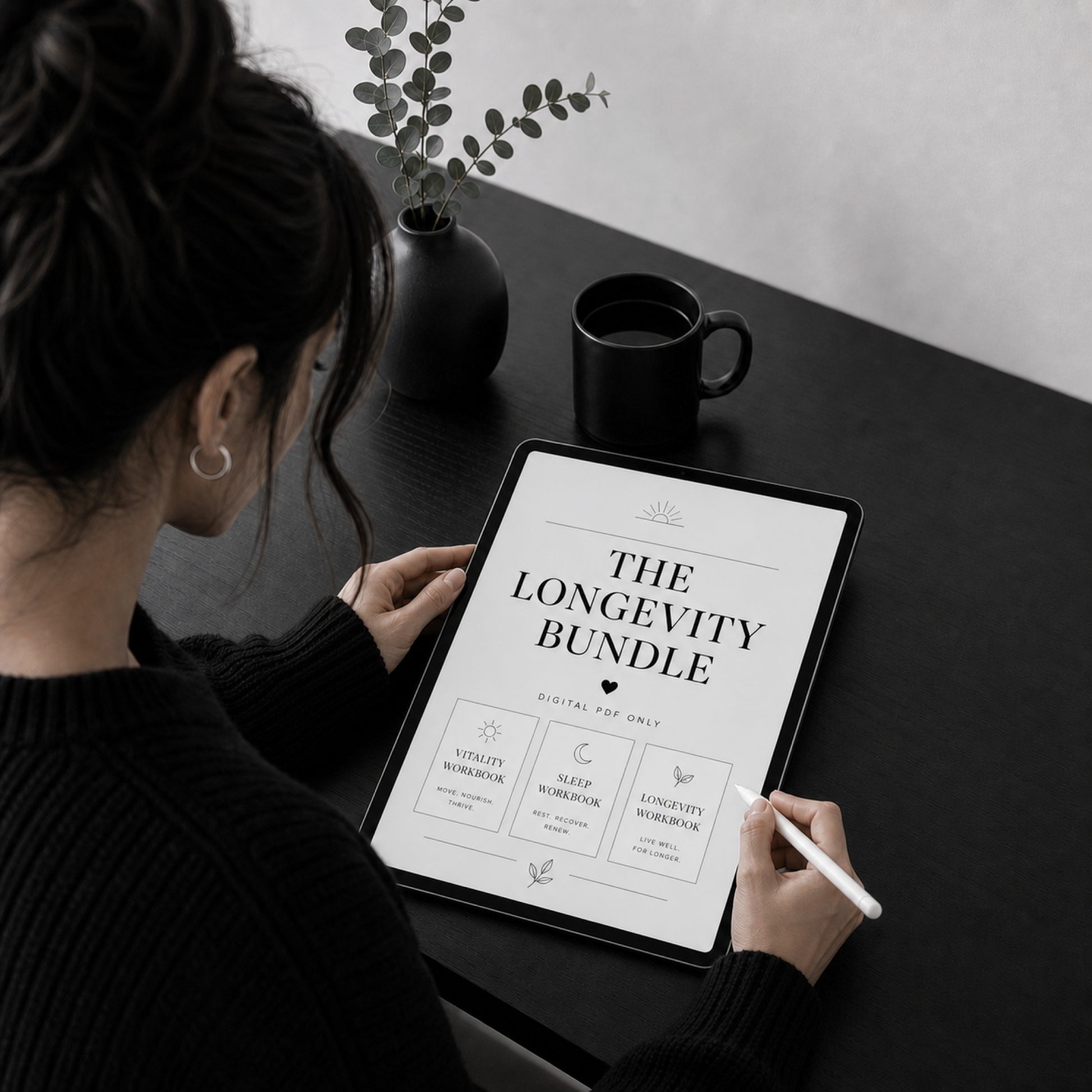 The Longevity Bundle vitality, sleep and longevity workbooks on a tablet — dark desk scene